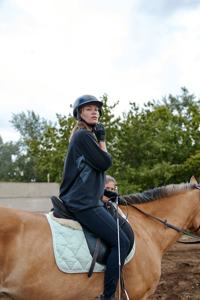 Confident woman riding a horse in a paddock, showcasing equestrian skills and focus.